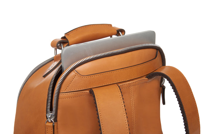 Tan Handcrafted with full grain American leather Padded backpack shoulder straps Roomy interior and front pocket Keychain attachment Interior organizer panel Fits up to a 15" laptop  Strap designed for easy carry on telescoping luggage handles Handcrafted with care in our own factory Natural leather lining Dimensions: 17" x 7" x 12" #color_tan